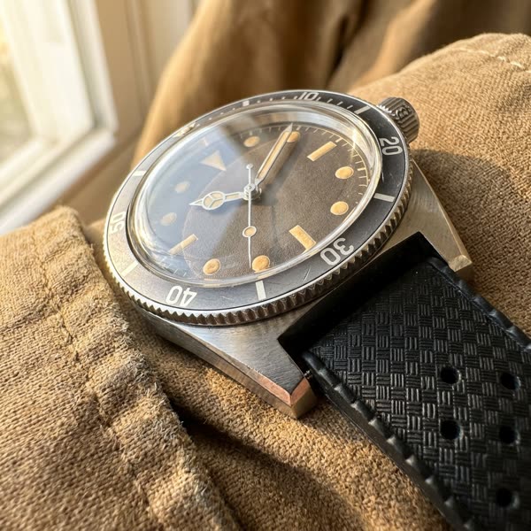 Close-up macro detail of a sterile vintage diver watch dial and bezel on waxed canvas.